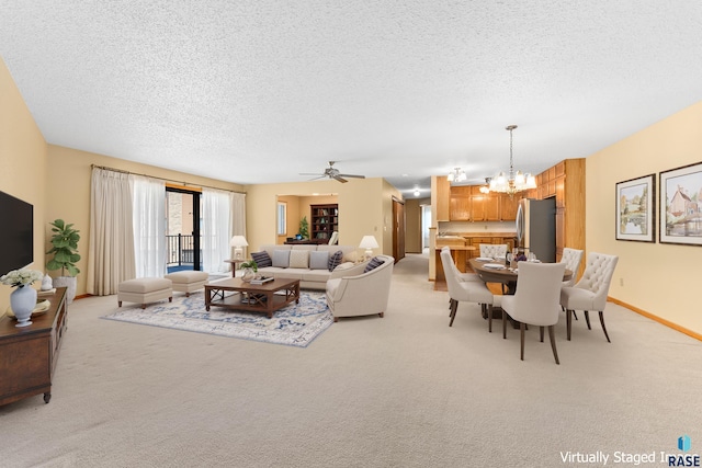 living room featuring ceiling fan with notable chandelier, baseboards, a textured ceiling, and light colored carpet