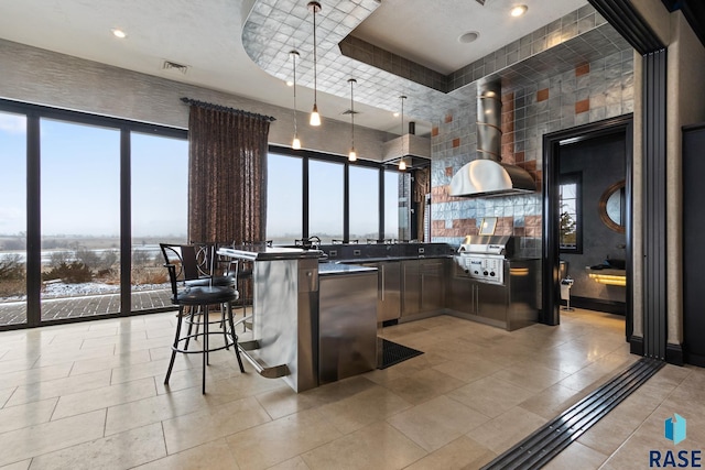 bar with light tile patterned floors, refrigerator, visible vents, wall chimney range hood, and pendant lighting