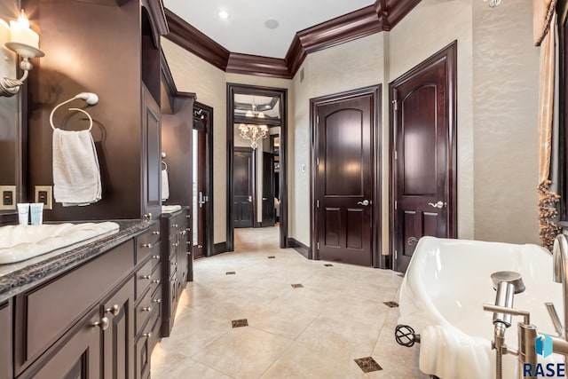 bathroom featuring a freestanding tub, vanity, baseboards, tile patterned floors, and crown molding