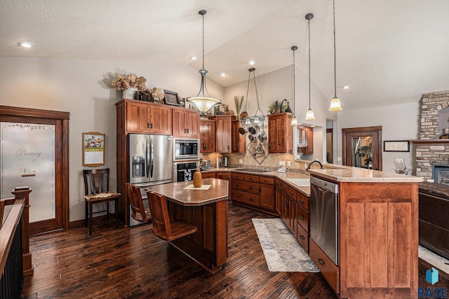 kitchen with brown cabinets, dark wood-style flooring, decorative light fixtures, a peninsula, and stainless steel appliances