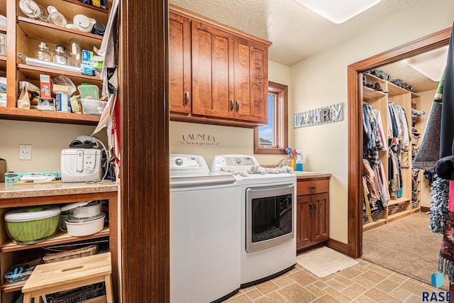 laundry room featuring baseboards, cabinet space, a textured ceiling, and washing machine and clothes dryer