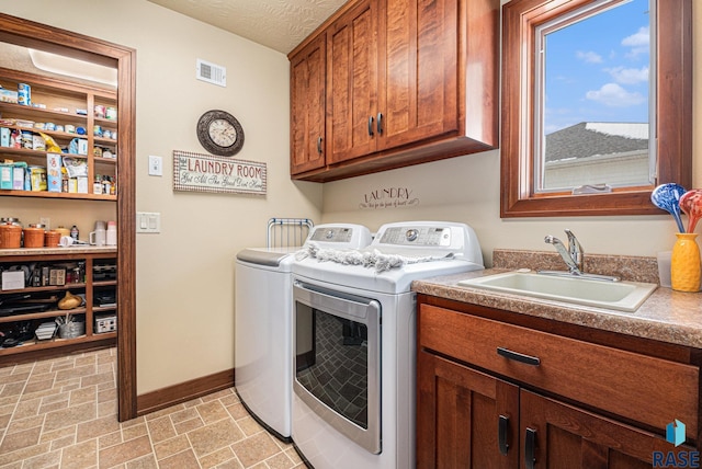 washroom featuring visible vents, cabinet space, a sink, washer and dryer, and baseboards