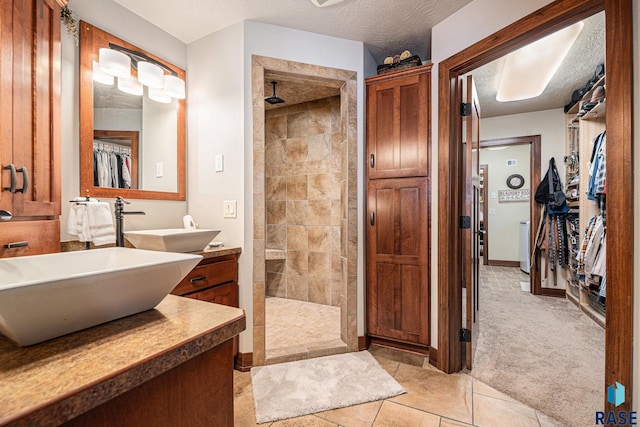 bathroom featuring a textured ceiling, a walk in shower, a sink, double vanity, and a walk in closet