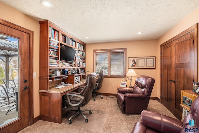 office featuring baseboards, a textured ceiling, and light colored carpet