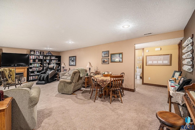 dining area with baseboards, visible vents, a textured ceiling, and light colored carpet