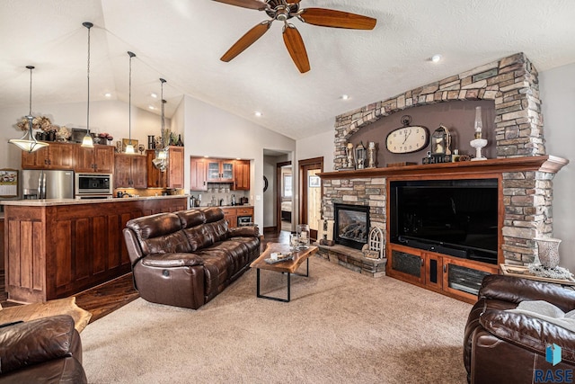 living area featuring light carpet, ceiling fan, a fireplace, and a textured ceiling