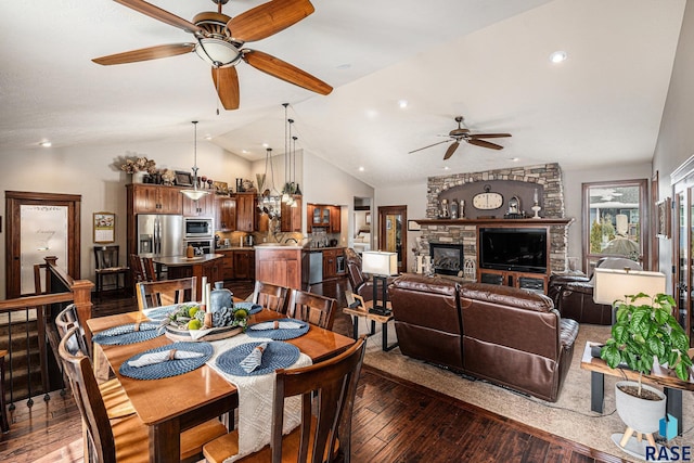 dining space with a stone fireplace, recessed lighting, wood finished floors, a ceiling fan, and vaulted ceiling