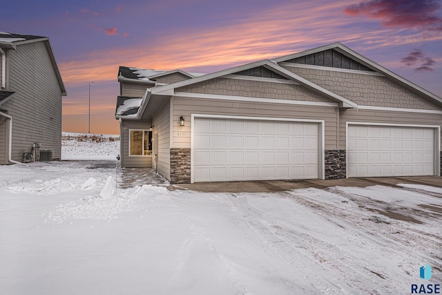 view of front of house with a garage, stone siding, and central AC unit