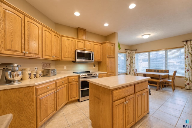 kitchen featuring light tile patterned floors, a center island, stainless steel appliances, light countertops, and recessed lighting