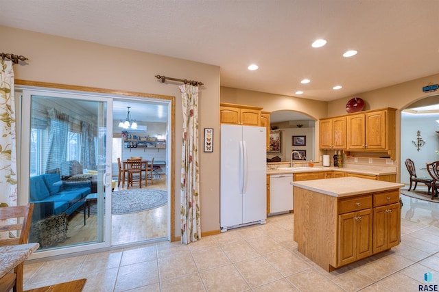 kitchen featuring arched walkways, white appliances, light countertops, hanging light fixtures, and a center island