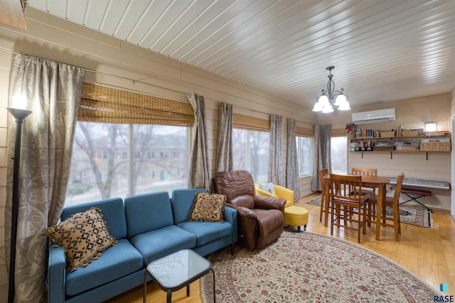 living room featuring an AC wall unit, a notable chandelier, and wood finished floors