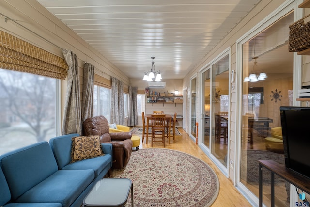 sunroom / solarium featuring a chandelier and a wall unit AC