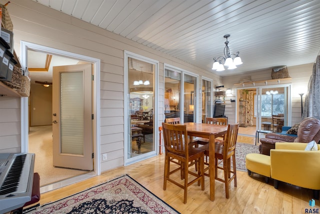 dining area with heating unit, wood walls, a chandelier, light wood-type flooring, and wooden ceiling