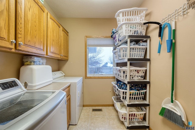 laundry room with light tile patterned floors, washing machine and dryer, cabinet space, and baseboards