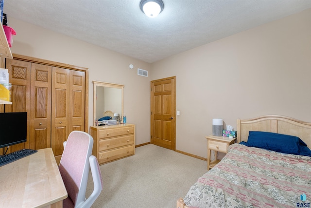 bedroom with light carpet, baseboards, visible vents, a textured ceiling, and a closet