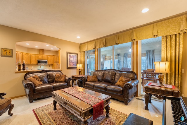 living room with arched walkways, light tile patterned floors, baseboards, and recessed lighting