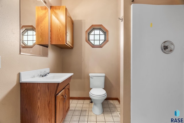 half bathroom with tile patterned flooring, baseboards, vanity, and toilet