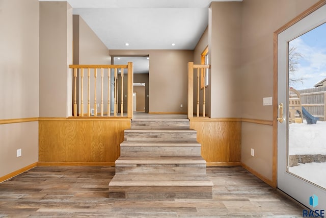 staircase with baseboards, wood finished floors, and recessed lighting