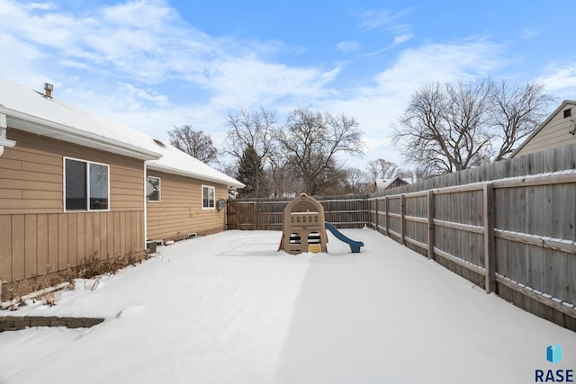 yard layered in snow featuring a playground and a fenced backyard