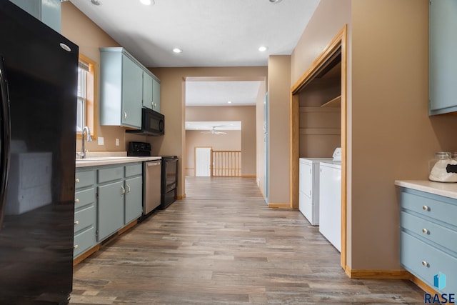 kitchen with washing machine and clothes dryer, light wood finished floors, light countertops, ceiling fan, and black appliances