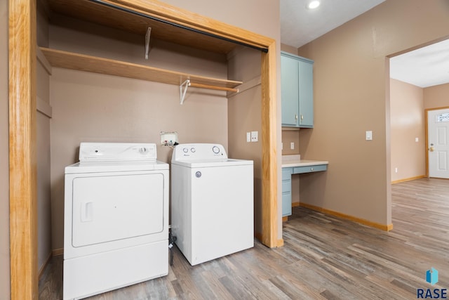 laundry area featuring wood finished floors, washing machine and clothes dryer, cabinet space, and baseboards