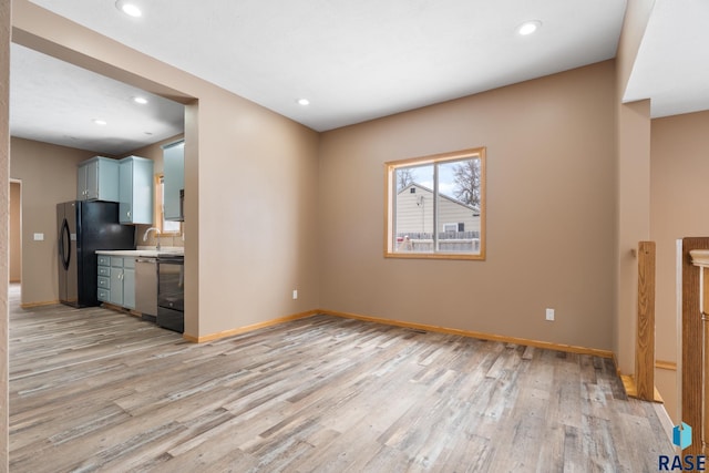 interior space with light wood finished floors, baseboards, light countertops, freestanding refrigerator, and dishwashing machine