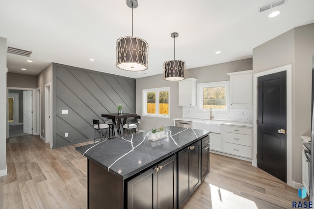 kitchen with backsplash, white cabinetry, a kitchen island, and visible vents