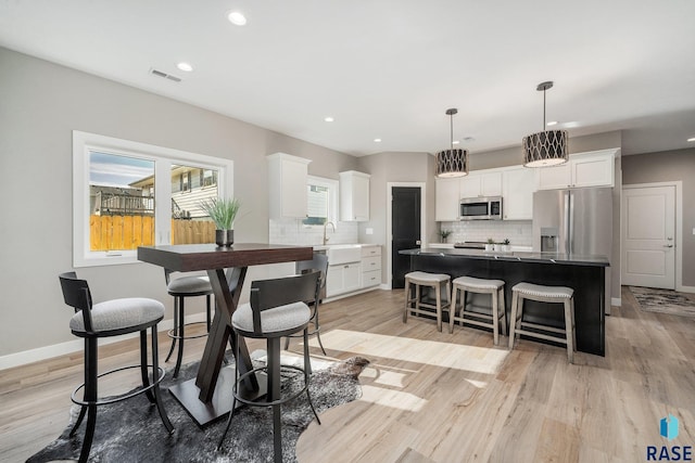 dining area with baseboards, recessed lighting, visible vents, and light wood-style floors