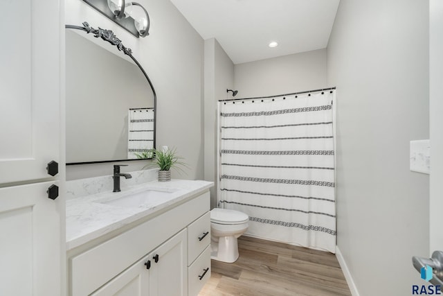 bathroom featuring a shower with shower curtain, toilet, vanity, wood finished floors, and baseboards