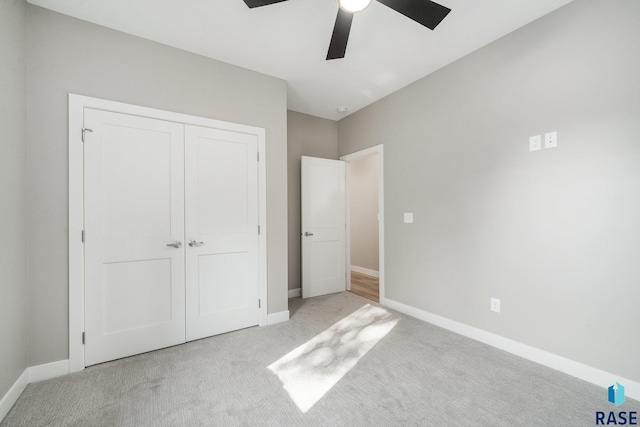 unfurnished bedroom featuring ceiling fan, a closet, light colored carpet, and baseboards