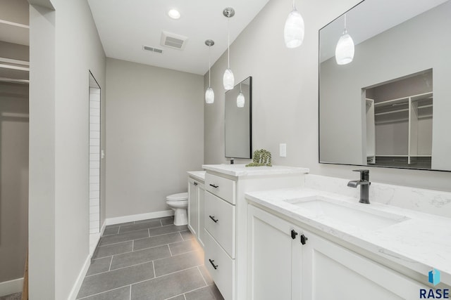 bathroom featuring toilet, baseboards, a spacious closet, and visible vents