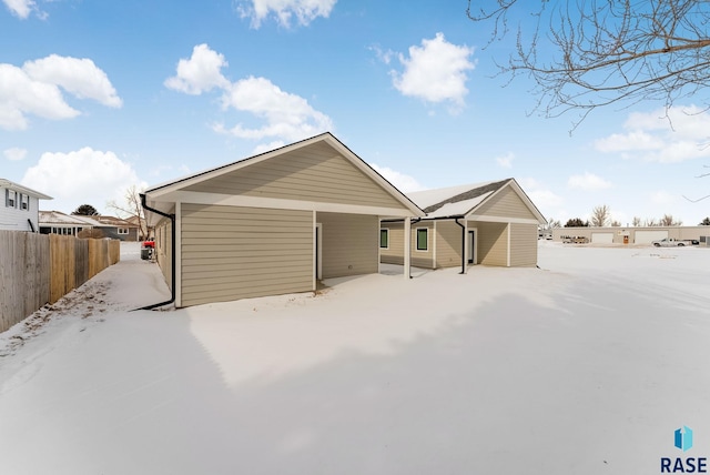 snow covered rear of property with fence