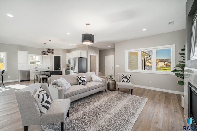 living room with light wood finished floors, recessed lighting, a fireplace, and baseboards