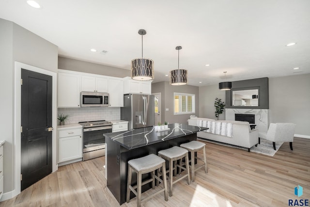 kitchen featuring a center island, a breakfast bar area, hanging light fixtures, appliances with stainless steel finishes, and white cabinets