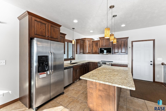 kitchen with tasteful backsplash, a kitchen island, appliances with stainless steel finishes, hanging light fixtures, and a sink