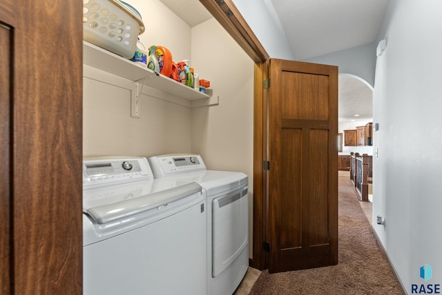 clothes washing area featuring arched walkways, laundry area, dark colored carpet, and washing machine and dryer