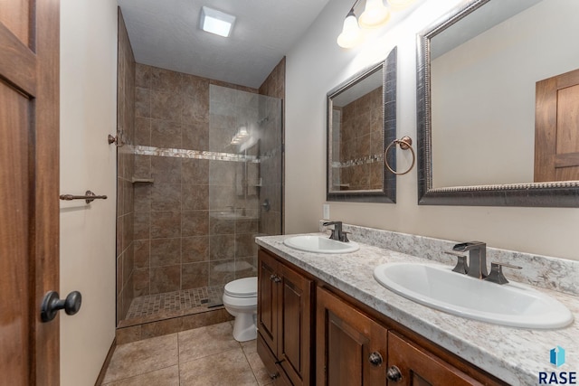 bathroom featuring tile patterned floors, a sink, toilet, and double vanity