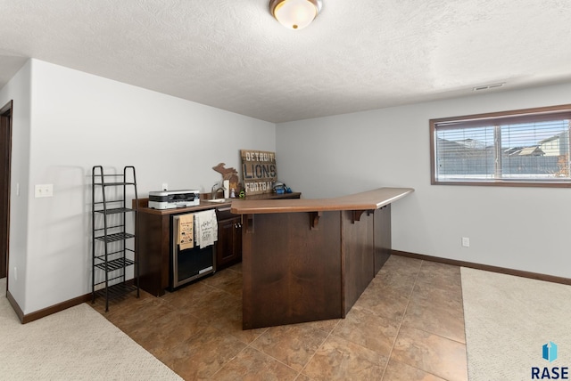 bar featuring visible vents, a textured ceiling, and baseboards