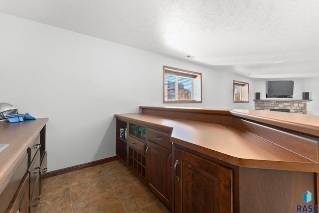 interior space featuring decorative backsplash, visible vents, a textured ceiling, and baseboards