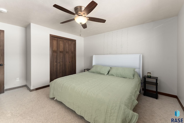 bedroom with a ceiling fan, a closet, light carpet, and baseboards