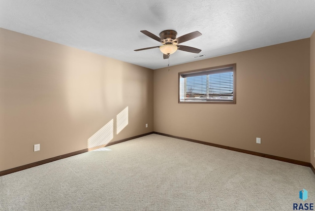 spare room featuring visible vents, light colored carpet, a ceiling fan, a textured ceiling, and baseboards