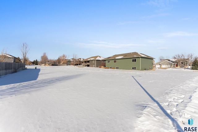 yard covered in snow featuring a residential view and fence