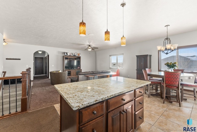 kitchen featuring a center island, arched walkways, pendant lighting, and open floor plan