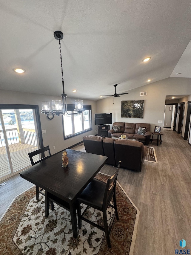 dining area featuring lofted ceiling, visible vents, a textured ceiling, and wood finished floors