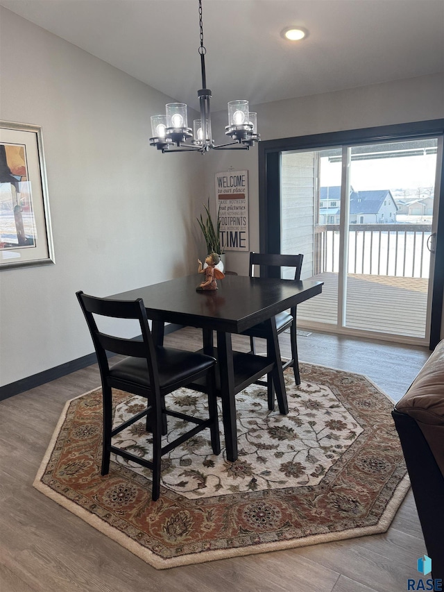 dining area featuring baseboards, wood finished floors, an inviting chandelier, vaulted ceiling, and recessed lighting