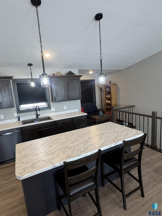 kitchen with a kitchen island, dark wood-type flooring, stainless steel dishwasher, pendant lighting, and a sink