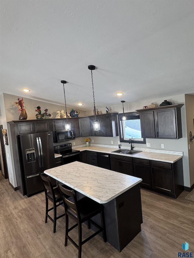 kitchen with a kitchen island, a sink, vaulted ceiling, hanging light fixtures, and black appliances