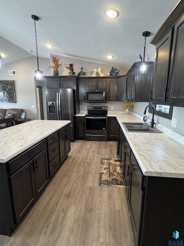 kitchen featuring stainless steel appliances, light countertops, decorative light fixtures, and a sink