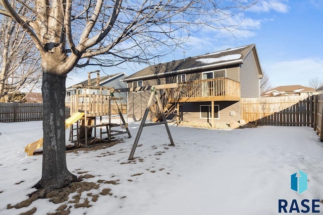 snow covered property featuring a playground and a fenced backyard