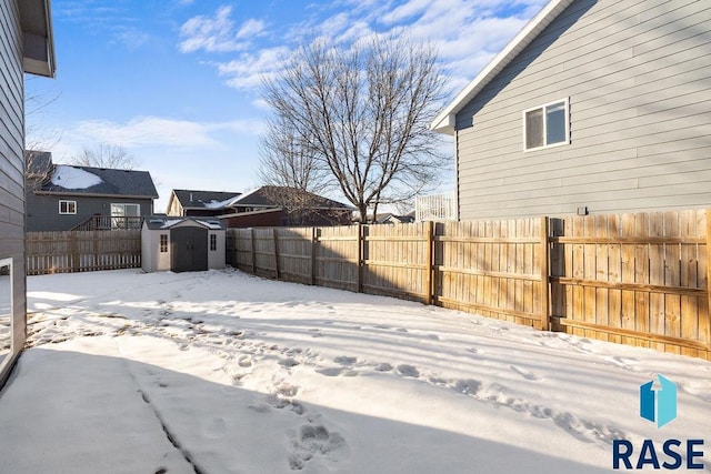 snowy yard with a storage shed, an outdoor structure, and a fenced backyard